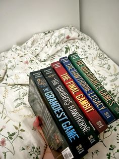 a hand holding a stack of books on top of a bed