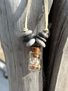 a glass bottle filled with rocks hanging from a wooden post