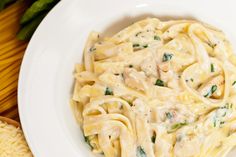 a plate of pasta with spinach and cheese on it next to bread slices, tomatoes and green beans