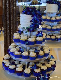 three tiered wedding cake with blue and white cupcakes