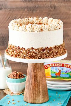 a cake with white frosting and pecans on top sitting on a wooden table