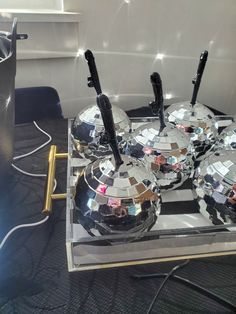 some disco balls are sitting on top of a mirrored stand with two microphones sticking out of them