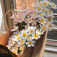 a bag filled with white and yellow flowers sitting on top of a window sill