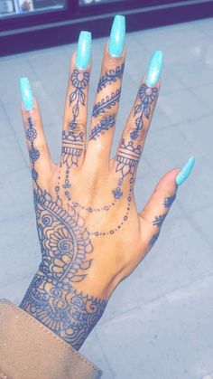 a woman's hand with blue nail polish and intricate designs on her fingers,