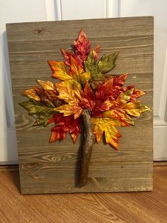 a wooden frame with a leaf tree on it's side and a white door in the background