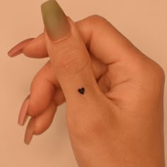 a woman's hand with a tiny black heart tattoo on her left thumb and finger