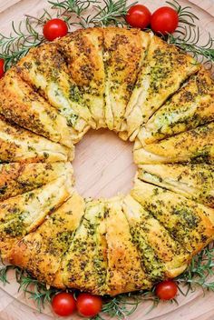 a bread wreath with tomatoes and herbs on the side, surrounded by rosemary sprigs