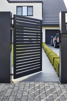 an open gate leading to a house with a car parked in the driveway behind it