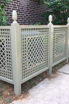 a white fence is next to a brick wall