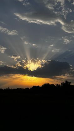 the sun is setting behind some clouds in the sky