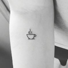 a black and white photo of a coffee cup tattoo on the left inner arm,