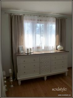 a white dresser sitting in front of a window