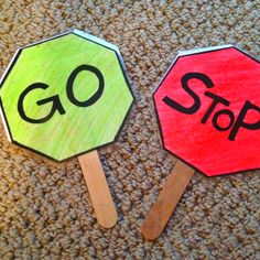 two paper stop signs sitting on top of a floor next to each other with the words go and stop painted on them