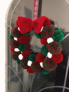 a knitted christmas wreath hanging on the front door