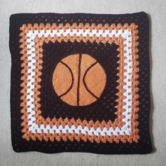 a crocheted square with a basketball design on the center is shown in black, white and orange