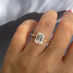 a woman's hand with a diamond ring on top of her finger and an engagement band