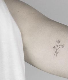 a woman's arm with a small flower tattoo on the left side of her arm