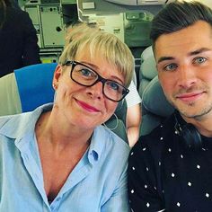 a man and woman sitting next to each other in an airplane seat with headphones on