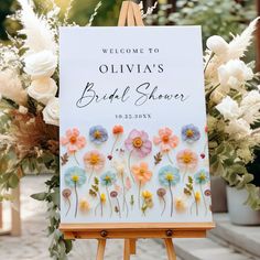 an easel with flowers on it and a sign that says, welcome to ollivia's bridal shower