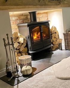 a wood burning stove sitting next to a pile of firewood in a living room