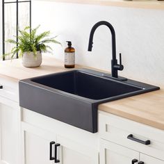 a black kitchen sink sitting on top of a counter next to a potted plant