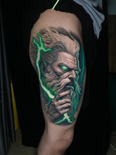 a man's arm with a green and black tattoo on it, depicting an evil demon