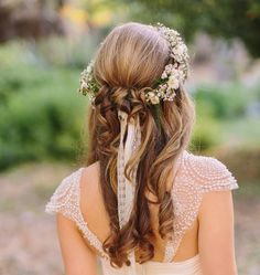 the back of a woman's head with long hair and flowers in her hair