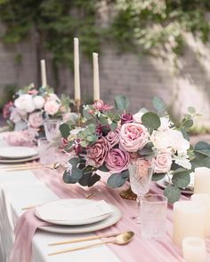 the table is set with pink flowers and candles