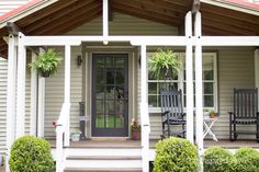 a porch with chairs and potted plants on the front steps, next to a house