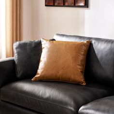 a black leather couch with a brown pillow