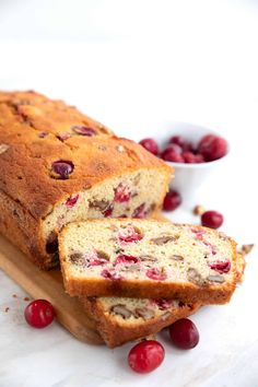 a loaf of cranberry bread on top of a cutting board next to some cherries