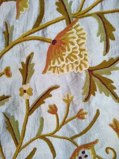 an embroidered piece of cloth with flowers and leaves on it