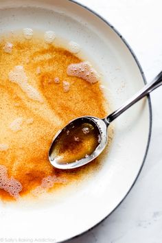 a white bowl filled with liquid and a spoon