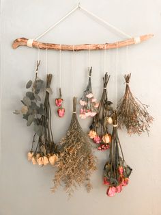 dried flowers hanging from a wooden stick on a wall