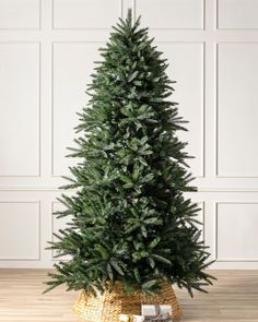 a small christmas tree in a wicker basket on a wooden floor next to a white wall