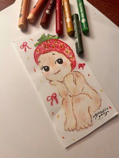 some crayons are sitting on top of a paper with a drawing of a baby