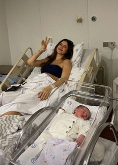 a woman laying in a hospital bed next to a baby