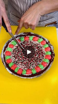 a person cutting into a cake on top of a yellow table cloth with a knife