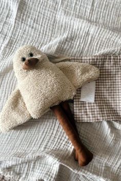 a stuffed animal laying on top of a bed next to a wooden stick and pillow