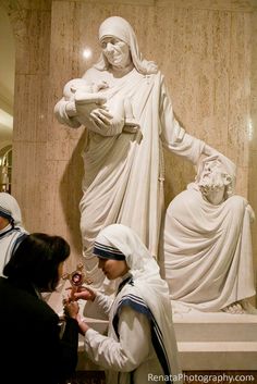 two women standing in front of a statue