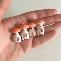 four tiny figurines in the shape of mushrooms on a person's hand