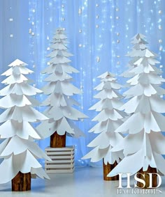 three paper christmas trees in front of a curtain