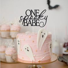 there is a pink cake with ghost decorations on it and one spooky babe sign