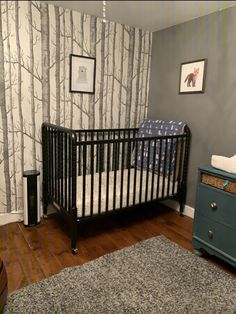 a baby's crib in the corner of a room with wood floors and wallpaper