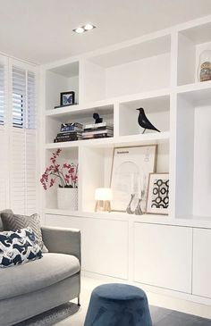 a living room with white shelving and blue stools in it's center