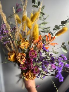 a vase filled with lots of different colored flowers and greenery next to a wall