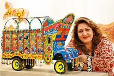 a woman leaning on a table next to a toy train with colorful decorations in it