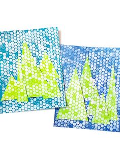 two pieces of paper with green and blue designs on them, one is folded to look like trees