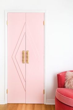 a pink door in the corner of a room with a red chair and fur pillow