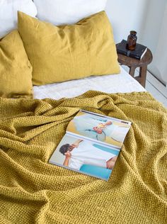 a magazine laying on top of a bed next to pillows